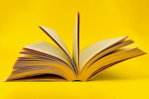 Old book laying on yellow paper Isolated gold background